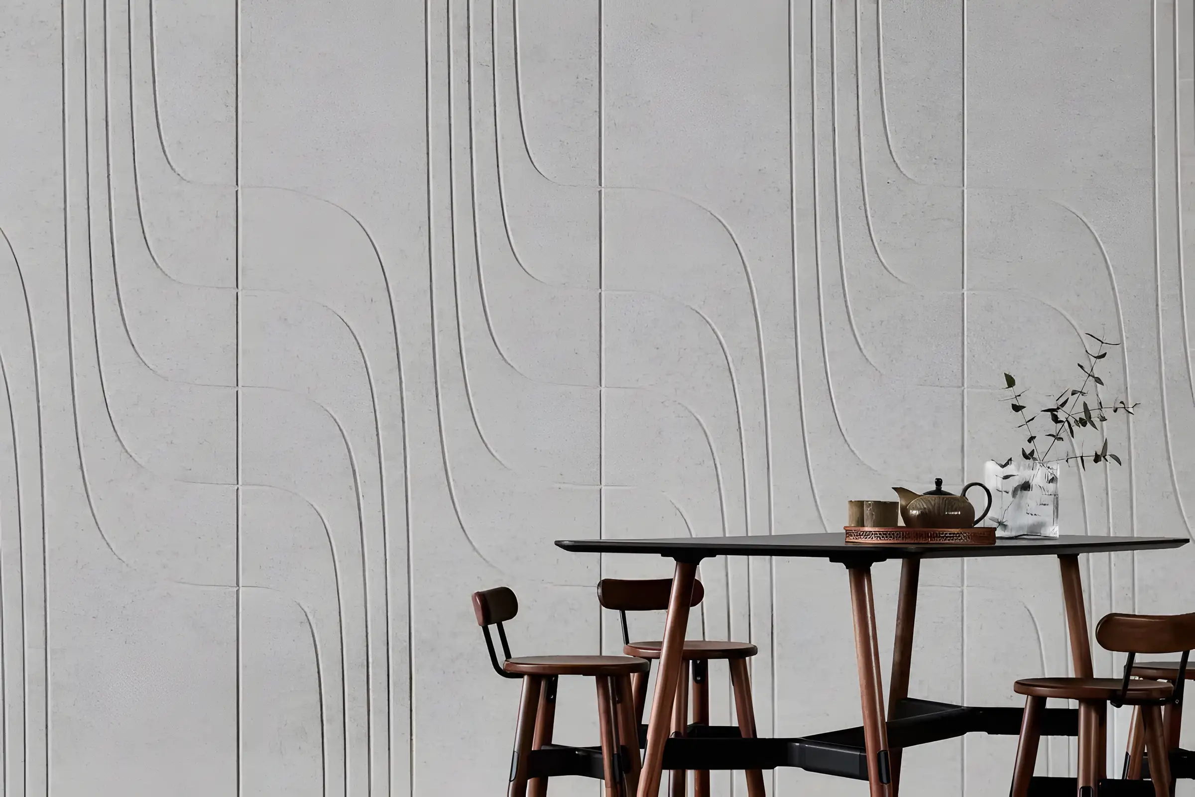 Wall clad with carved acoustic panels behind a wooden dining table